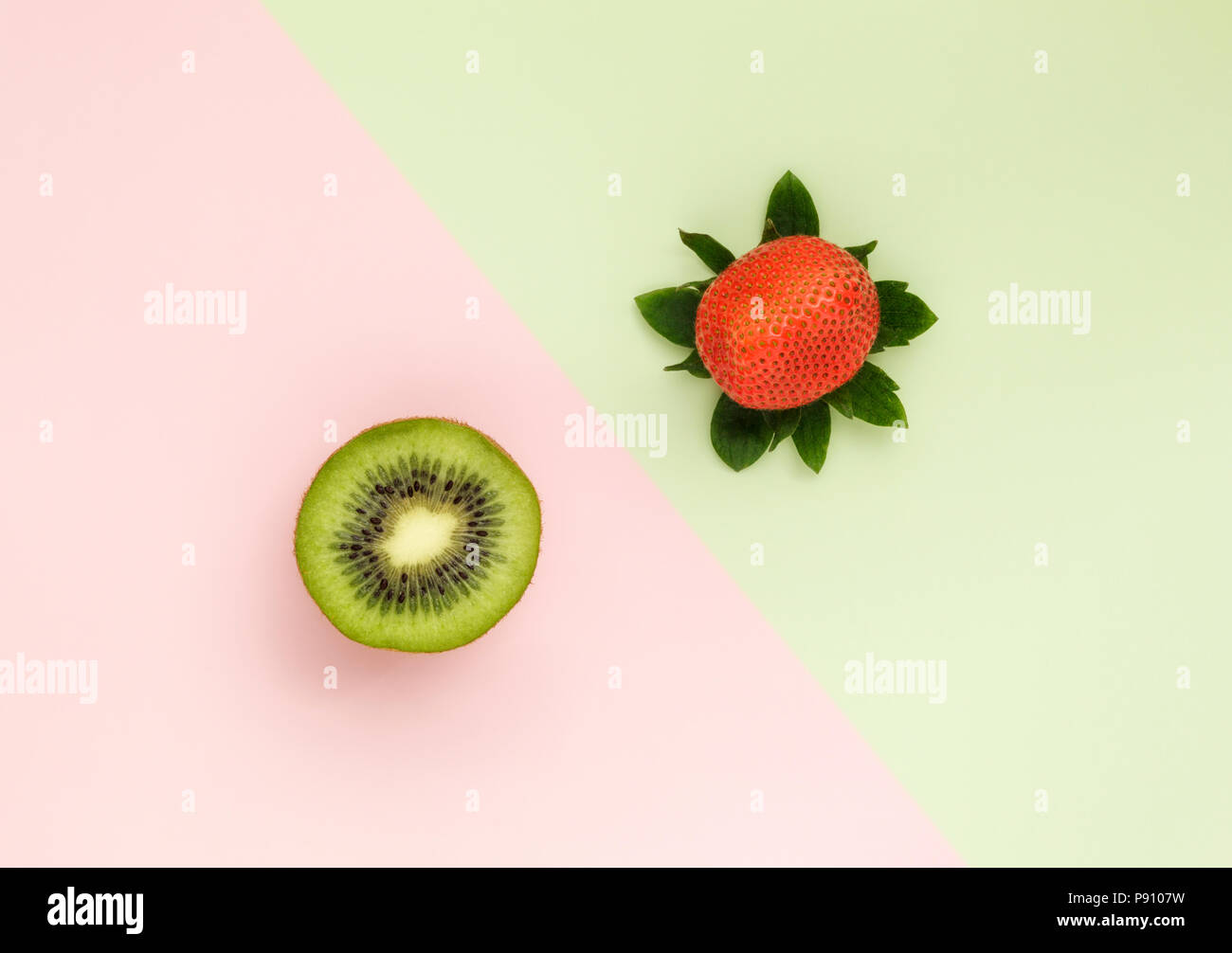 Una mitad de kiwi y fresa uno sobre fondo de color duo Foto de stock