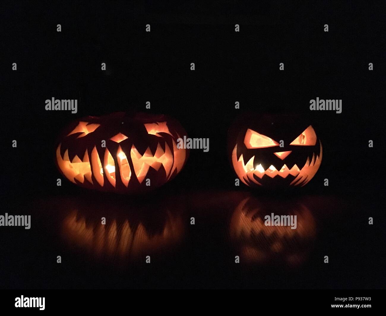 Scary Halloween calabazas aislado sobre un fondo negro. Miedo rostros resplandecientes trick or treat. Foto de stock