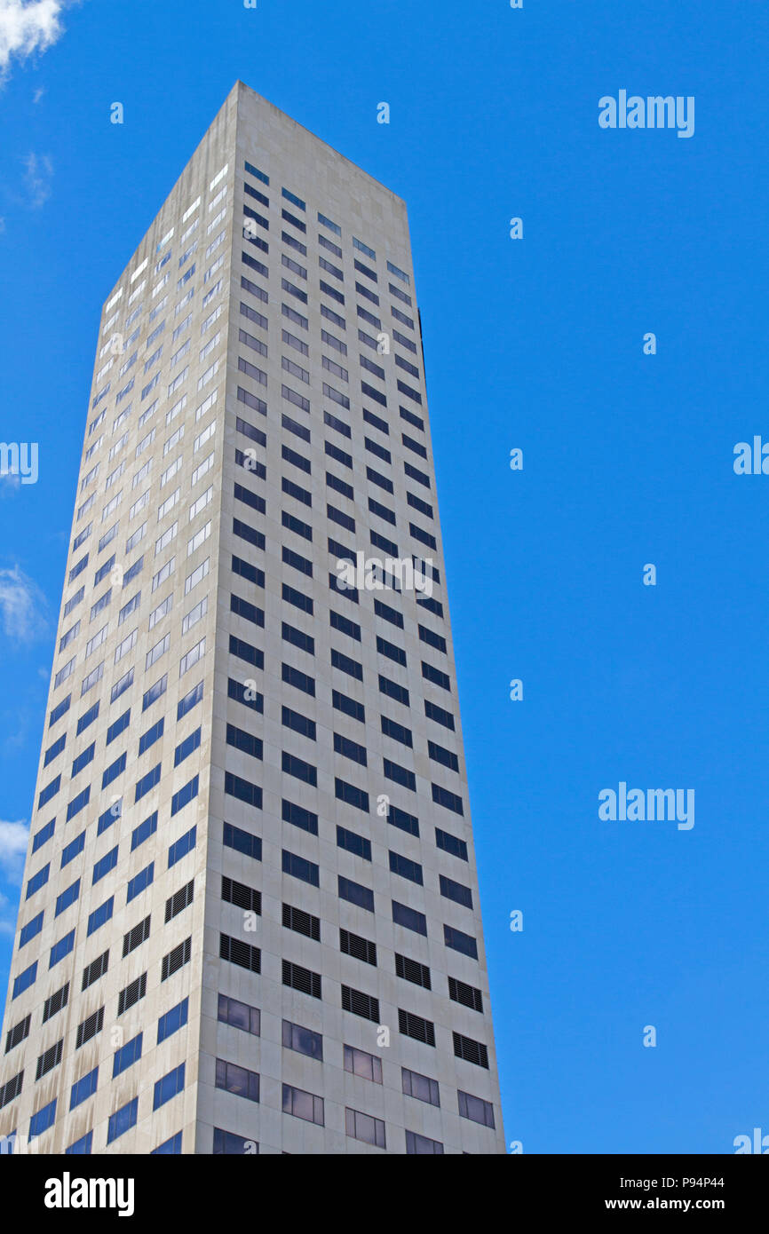 Un edificio alto en una ciudad de rascacielos, contra el cielo azul, con orientación vertical, ejemplo de arquitectura moderna Foto de stock