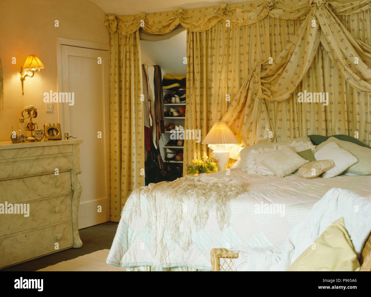 Abra la cortina para mostrar almacenamiento oculto detrás de la cama con  crema cortinas estampadas en pequeño dormitorio Fotografía de stock - Alamy