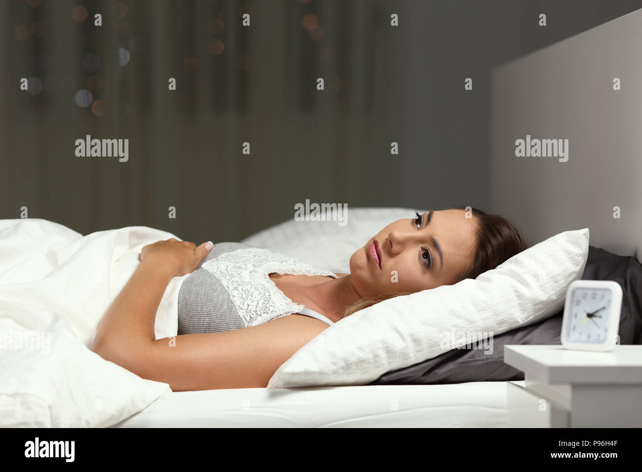 Insomniac mujer incapaz de dormir acostado en una cama en la noche en su domicilio. Foto de stock