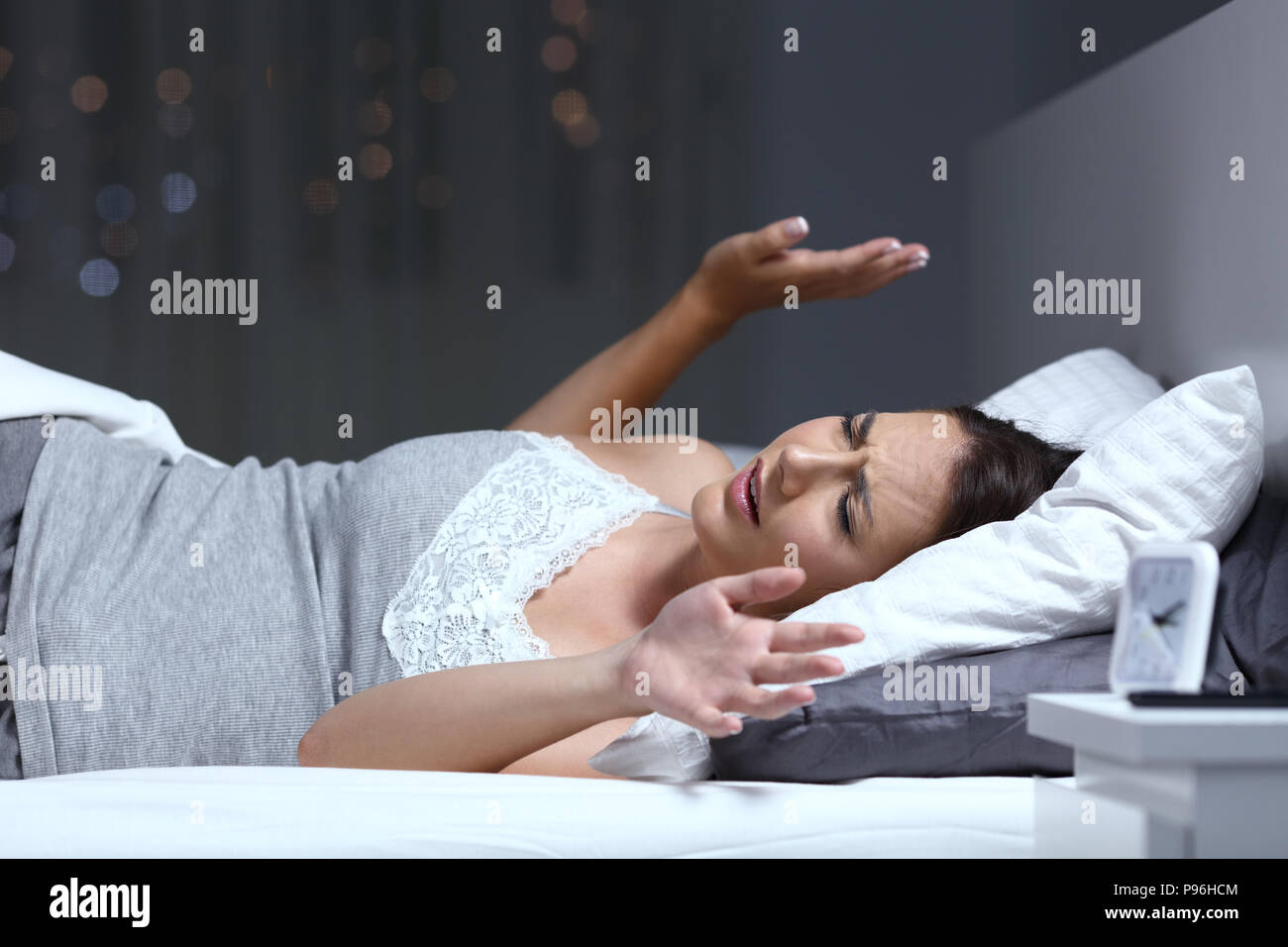La mujer tiene una pesadilla tumbado en la cama en la noche en su domicilio. Foto de stock