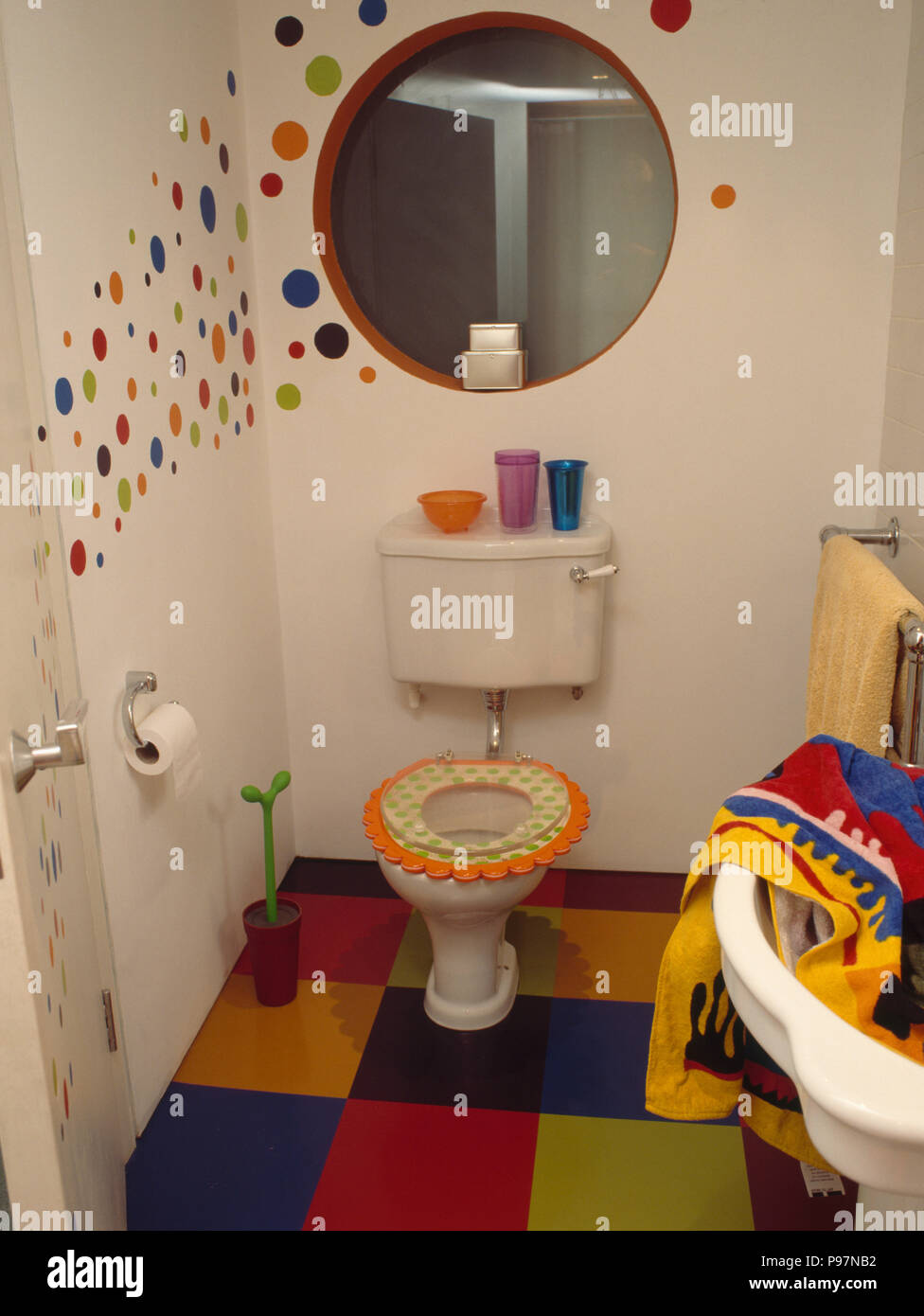 Espejo circular encima de wc con asiento de novedad en un cuarto de baño  moderno con suelos de mosaico multicolor y manchas pintados en la pared  Fotografía de stock - Alamy