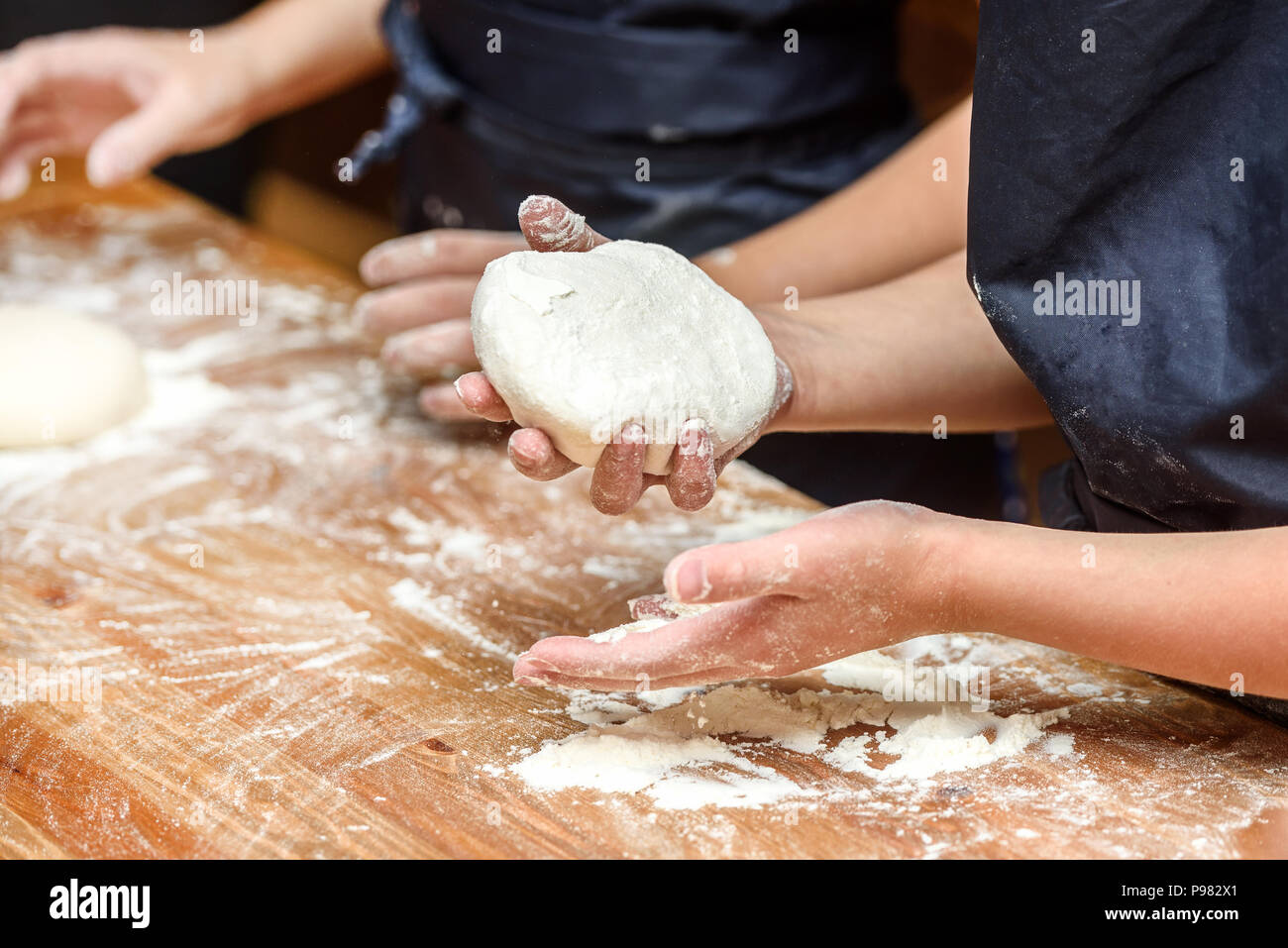 Close-up de las manos de los niños, la preparación de masa para pizza. Pizza, los niños y el concepto de cocina - Los niños hacen pizza. Foto de stock