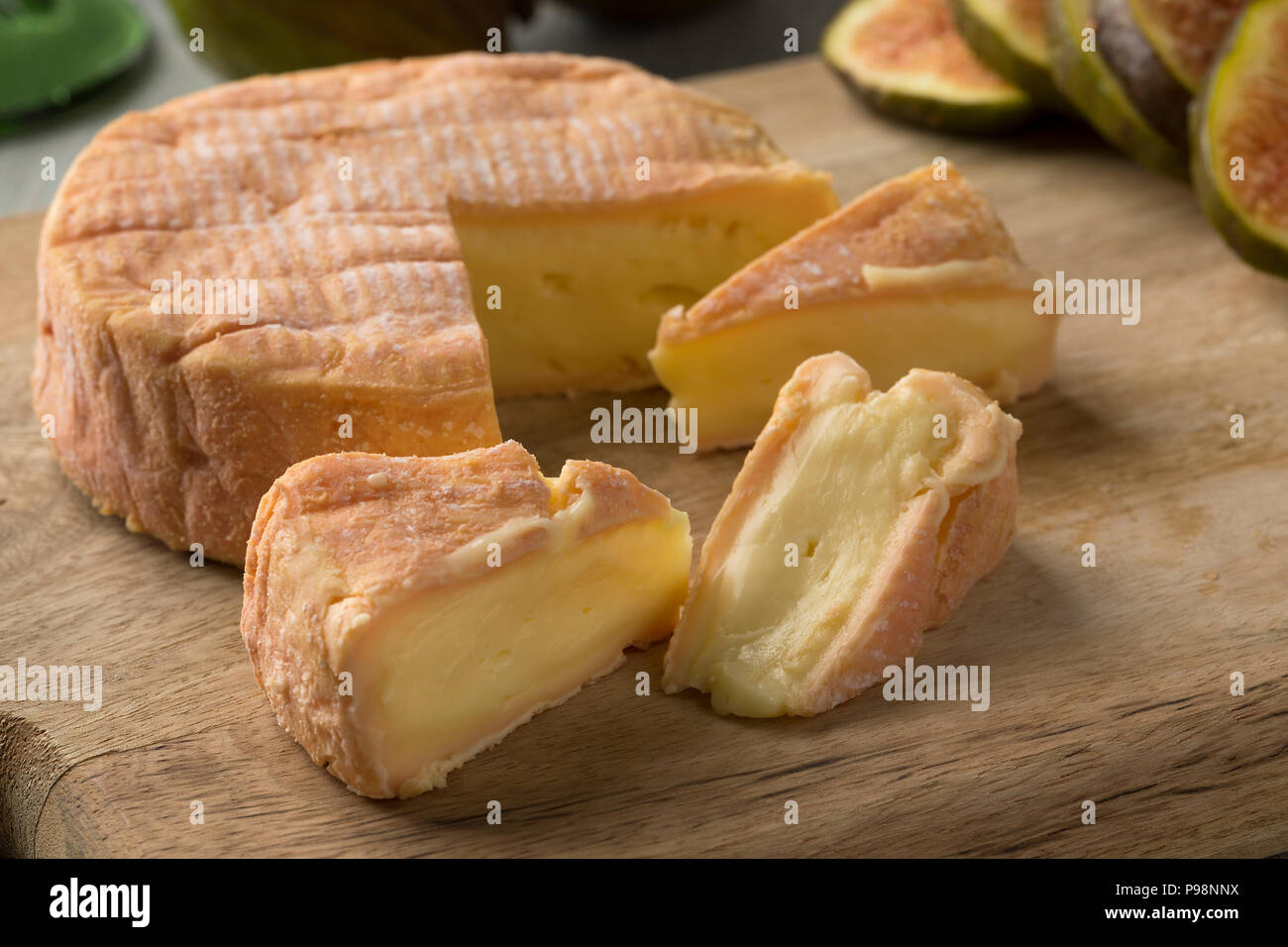 Trozo de queso maduro petit Munster cerca e higos frescos en el fondo para el postre Foto de stock