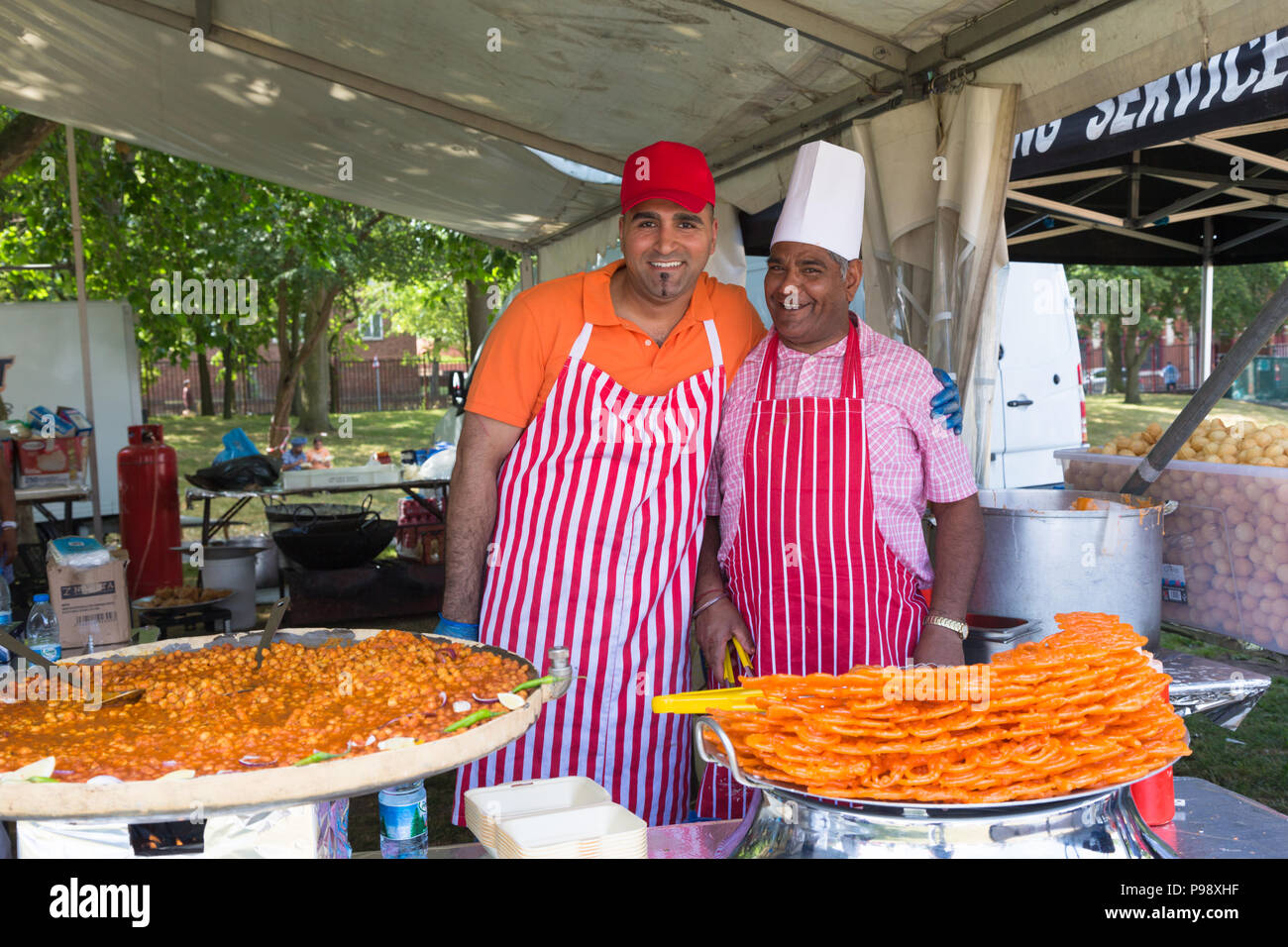 Dos chefs o cocineros en un puesto de venta de comida en la calle de comida asiática y aperitivos UK Foto de stock