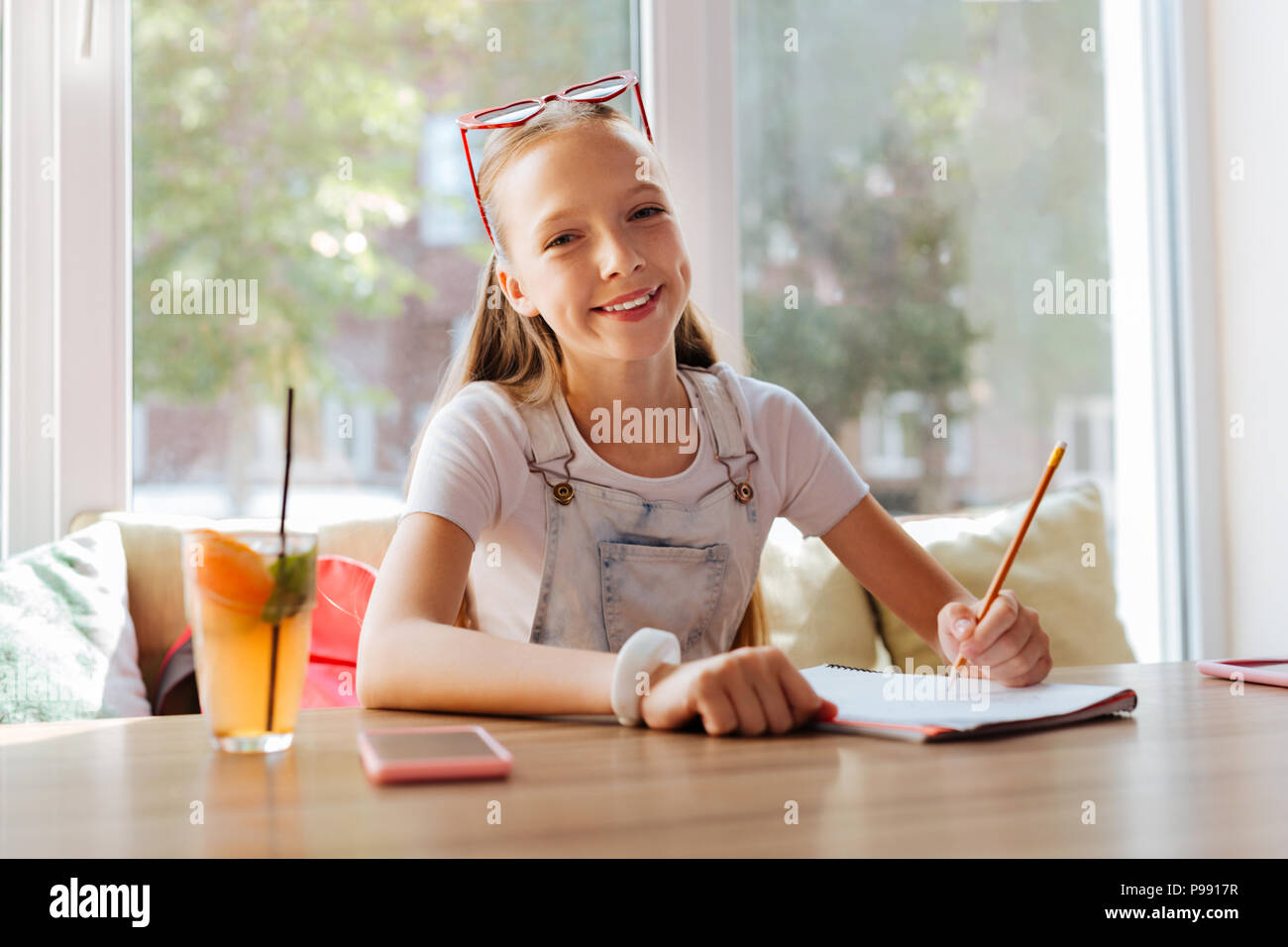 Transmisión de dark-eyed girl dibujo naturaleza sentado en la cafetería Foto de stock