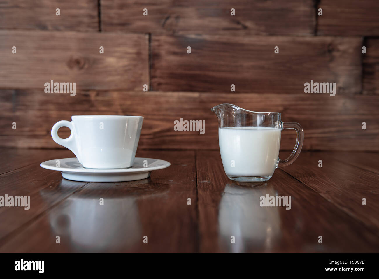 Leche en la jarra de leche de vidrio con taza blanca Foto de stock