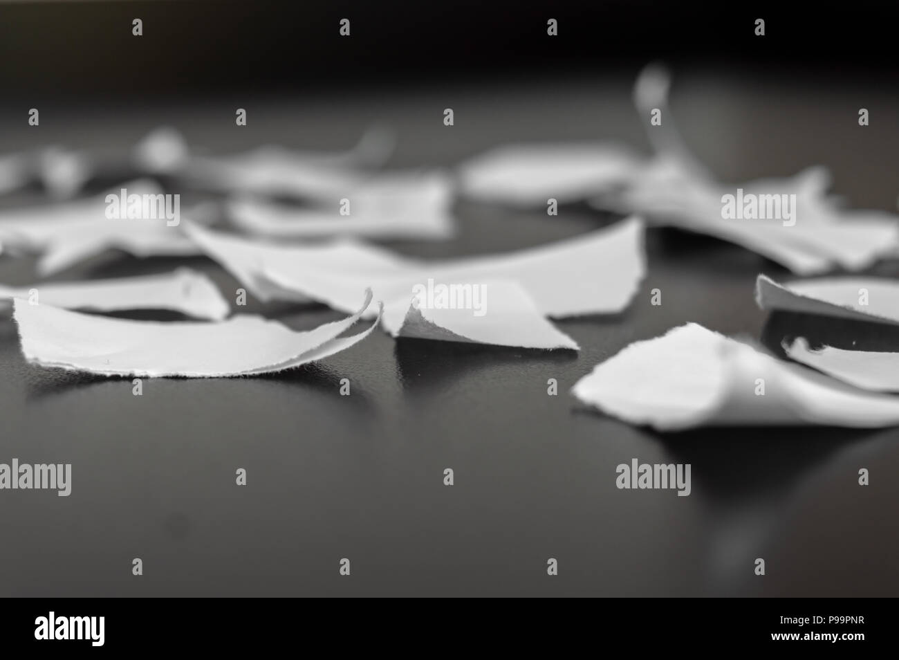 Rip en muchos pedazos de papel sobre una superficie negra Foto de stock