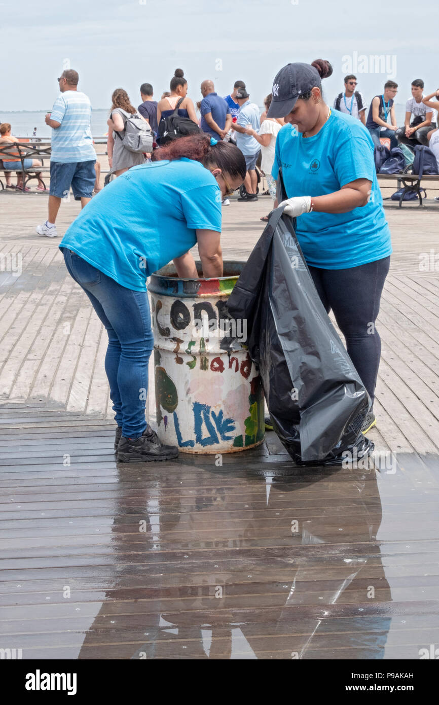 Dos mujeres de la ciudad de Nueva York Departamento de Parques empleados vaciar una papelera en el Boardwalk en Coney Island, Brooklyn, Nueva York. Foto de stock