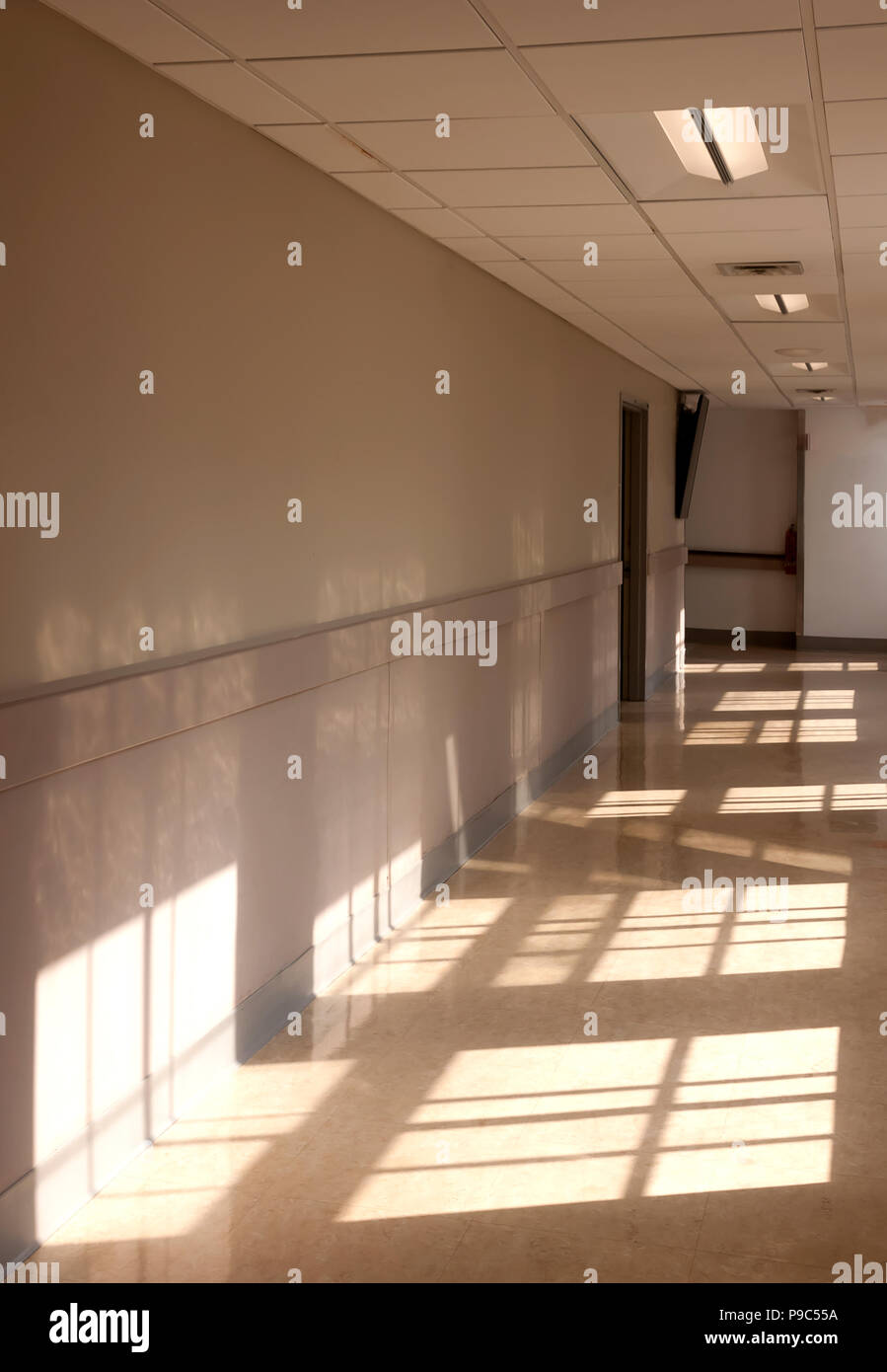 La luz del sol brillando a través de ventanas que dan a un pasillo. Foto de stock