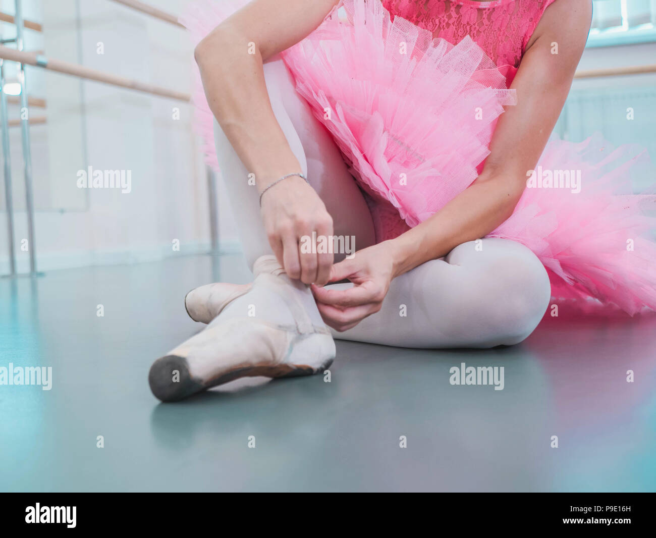 Joven bailarina en rosa tutu traje blanco envolturas de cintas de seda de  capota de lona zapatos de ballet pointe y lazos. Mujer preparando para  clases de formación de baile en el