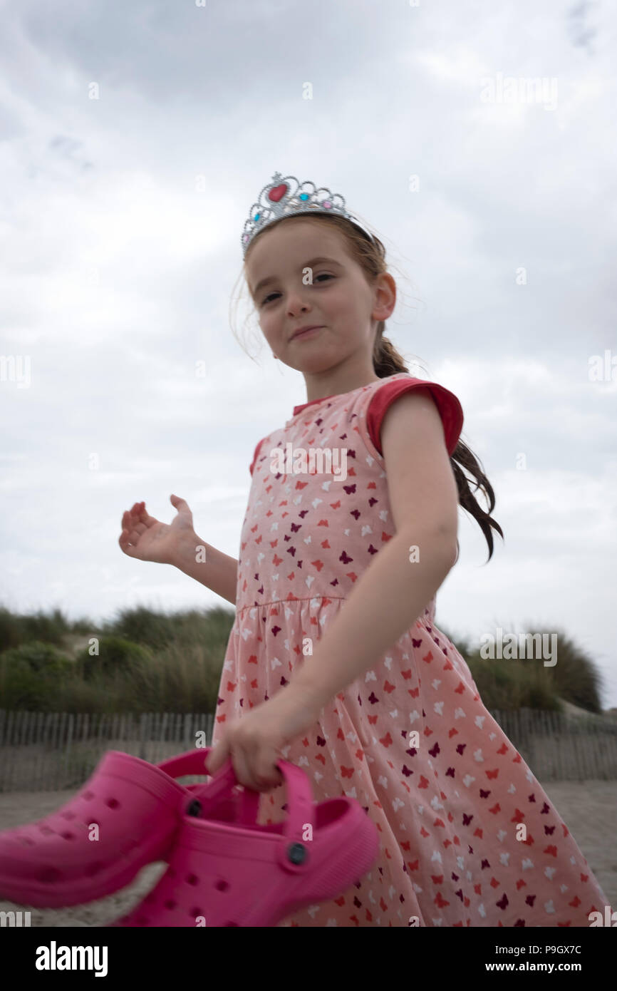 Divertido golpe de una niña de 4 años caminando con cabello largo rojo llevaba una tiara, sosteniendo un par de crocs rosa en la Fotografía de stock - Alamy