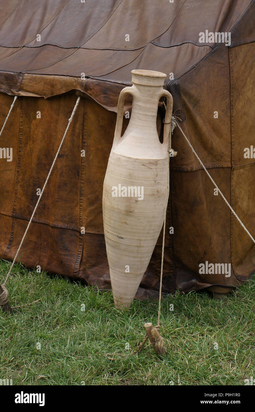Un gran vino de cerámica ánfora, apoyado en la esquina de una tienda del ejército romano de cuero. Foto de stock