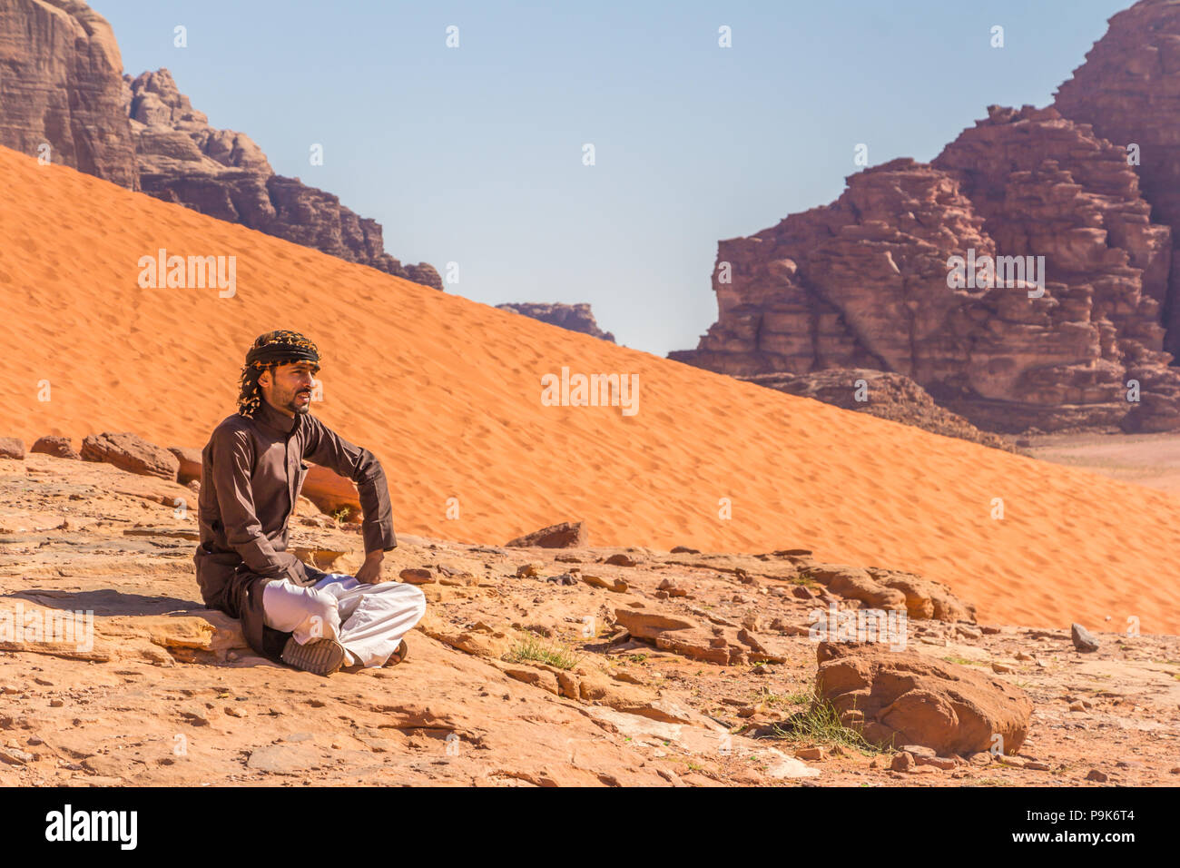Wadi Rum, Jordania - Abril 30, 2016: hombre beduino está descansando sobre una roca en el desierto de Wadi Rum en Jordania Foto de stock