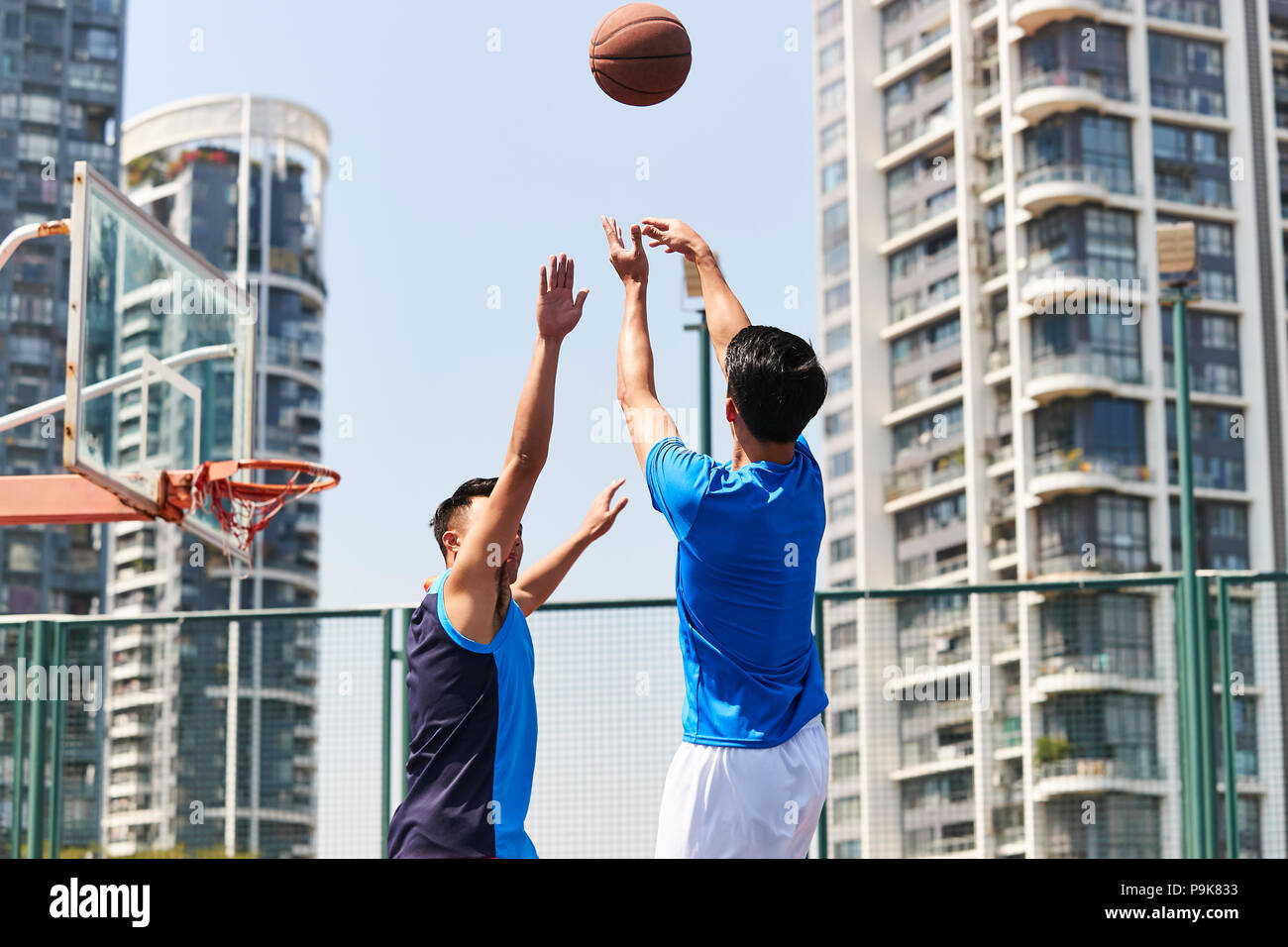 Los jóvenes adultos de Asia jugadores jugando baloncesto en el tribunal exterior. Foto de stock