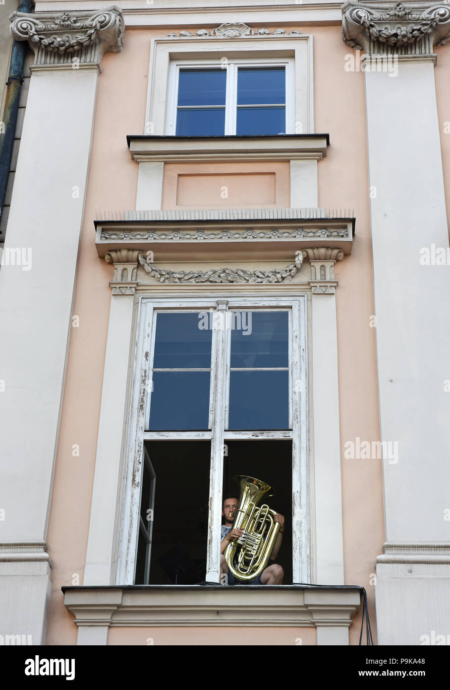 Músico tocando realizar desde Windows Apartamento En Cracovia, Polonia. Foto de stock