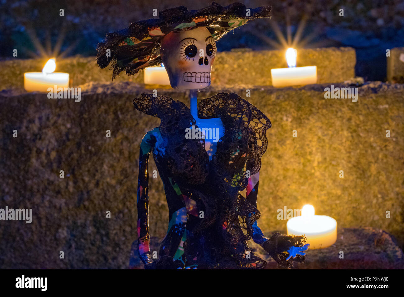 La Calavera Catrina doll en la noche rodeado de velas para el Día de