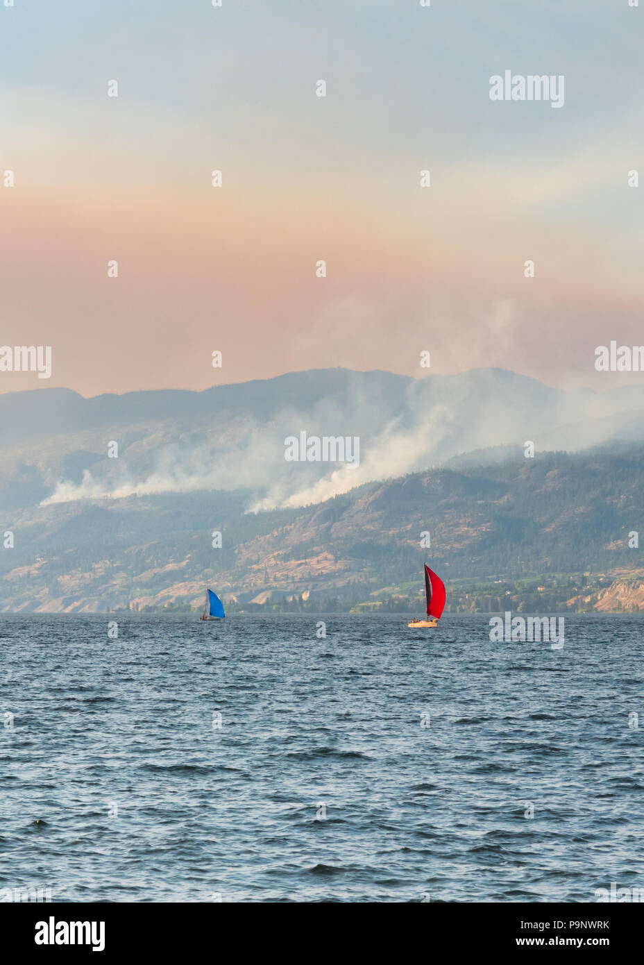 Veleros en el Okanagan Lake con humo de varios relámpagos provocó incendios forestales en las montañas por encima de Naramata Foto de stock