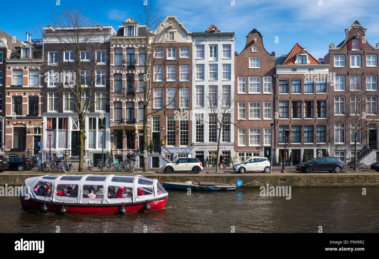 Casas de canal estrecho y alto y una excursión en barco de cruceros turísticos en un canal de Amsterdam, Países Bajos, Europa Foto de stock