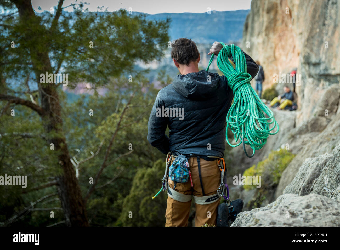 Vista trasera shot masculino de escalador llevar la cuerda al acantilado, Siurana, Cataluña, España Foto de stock