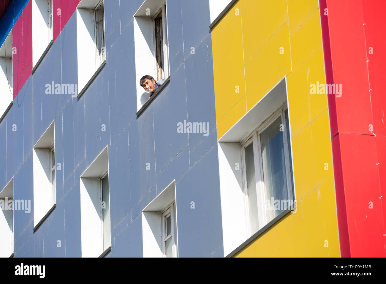 Hombre compañeros fuera de la ventana de la vivienda en bloque Provideniya colorida, Rusia Foto de stock