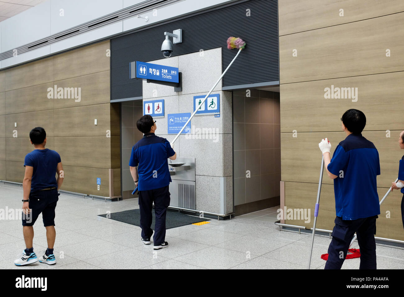 Los trabajadores - uno con un extra-largo rp - Limpieza de el aeropuerto internacional de Incheon en Seúl, Corea del Sur. Foto de stock