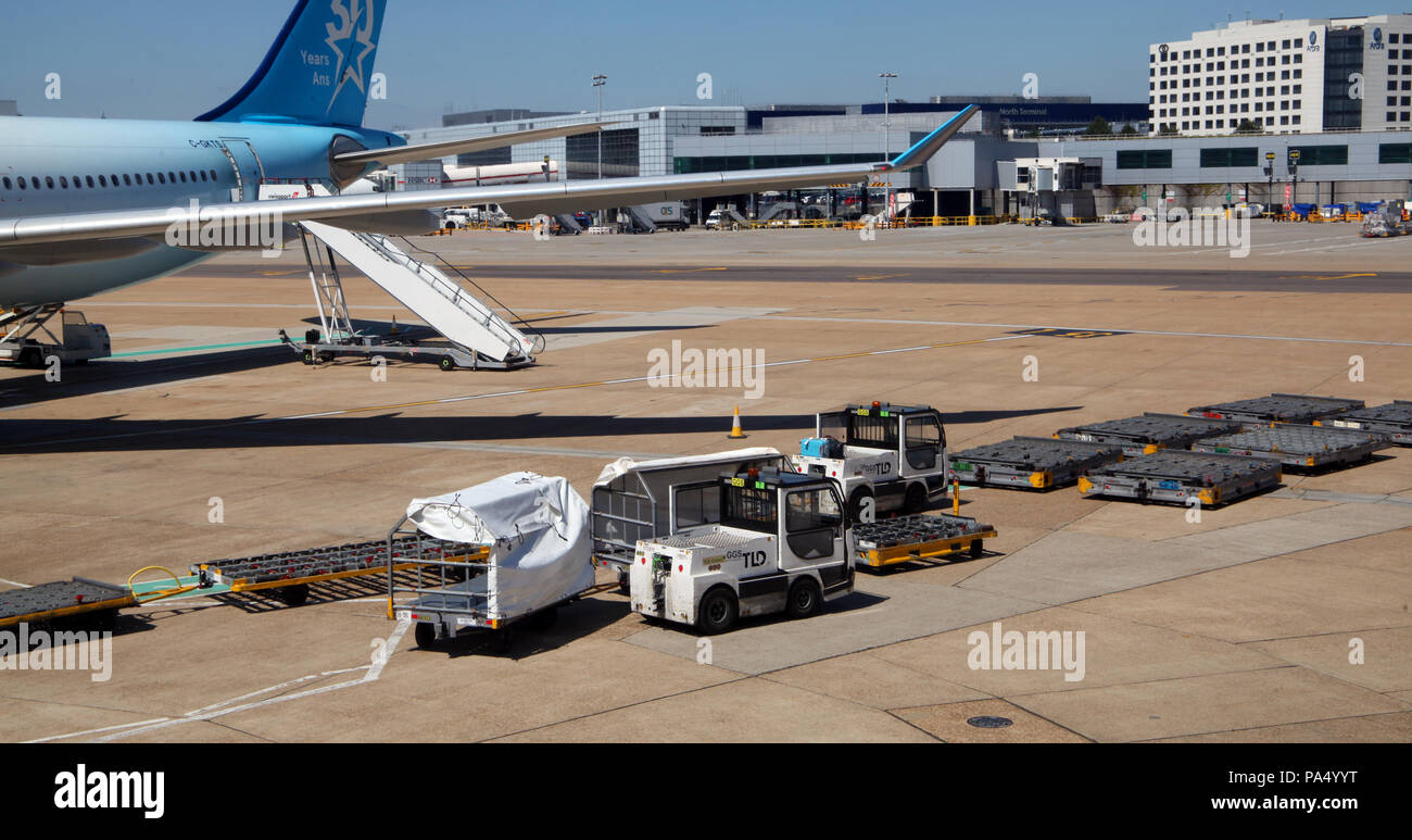 Equipo para gestionar el equipaje de los pasajeros en el delantal al Aeropuerto Gatwick de Londres Foto de stock
