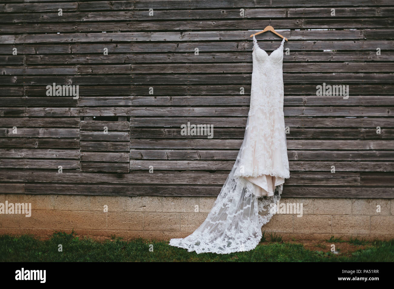 Vestido de novia colgado delante de una pared de madera Foto de stock