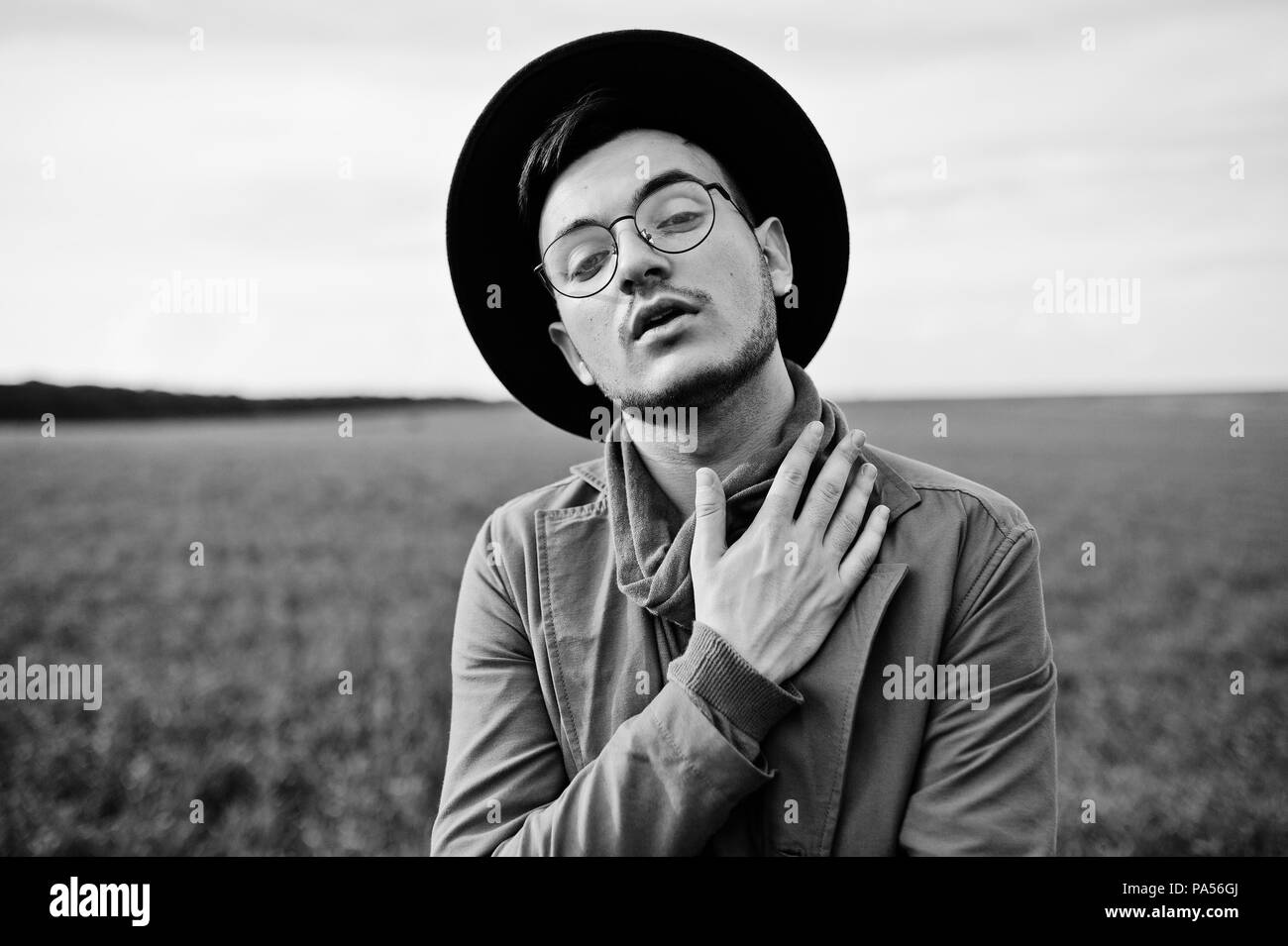 En vidrios, hombre elegante chaqueta marrón y sombrero plantean sobre campo verde. Foto de stock