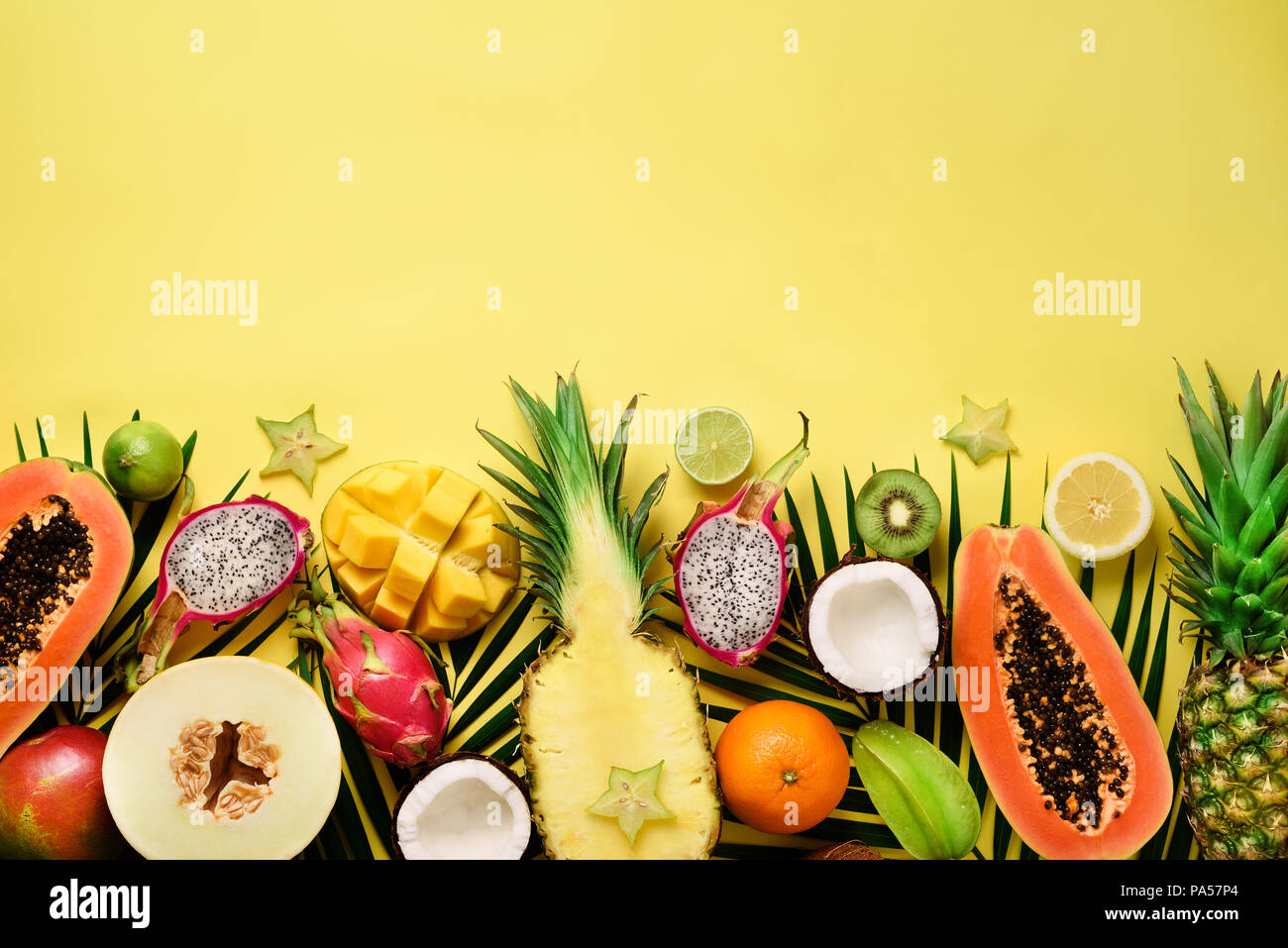 Las frutas exóticas y tropicales de hojas de palma sobre fondo amarillo  pastel, papaya, mango, piña, banano, carambola, fruta del dragón, kiwi,  limón, naranja, m Fotografía de stock - Alamy