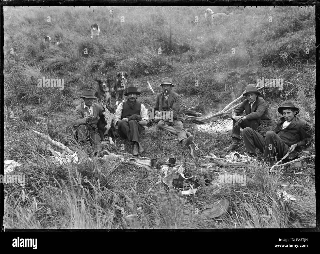 108 Grupo de hombres con sus perros, alrededor de un fuego de campamento. El hombre la segunda desde la izquierda sostiene una salvaje lechón en su regazo. En la granja de ovejas, Mendip Hills. ATLIB 284080 Foto de stock