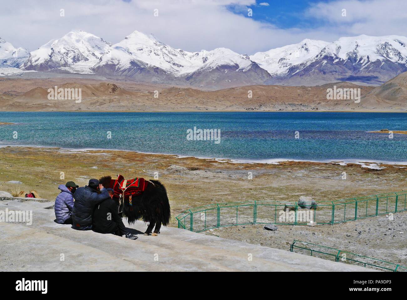 Chino pueblo nómada de grupo minoritario en el lago Karakul en Xinjiang con montañas nevadas de fondo. Foto de stock