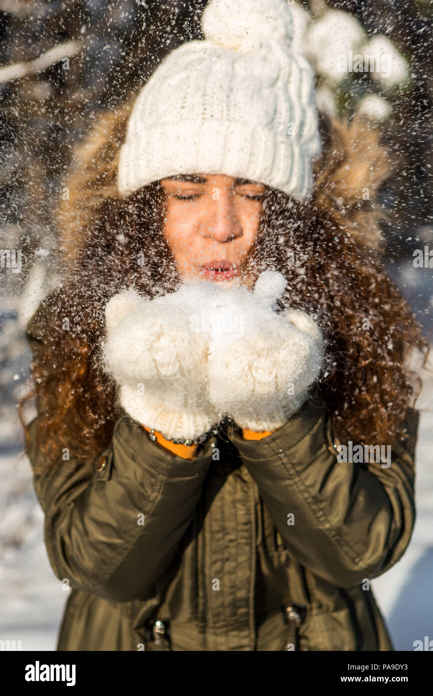 Retrato de una dama hermosa morenita jugando con nieve en invierno