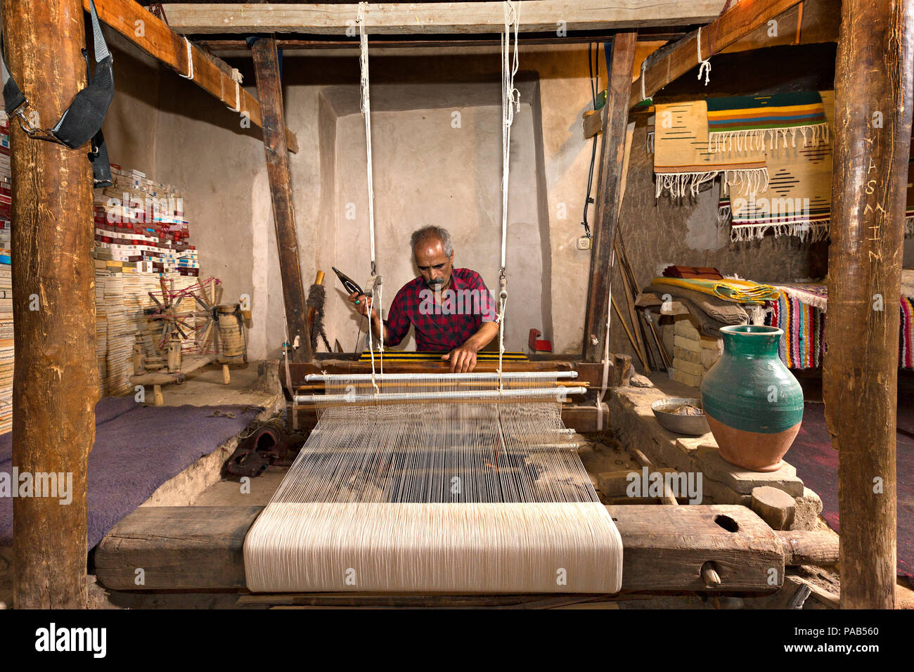 El hombre iraní teje telas conocido como Aba, en forma tradicional, en la localidad de Naein, Irán. Foto de stock