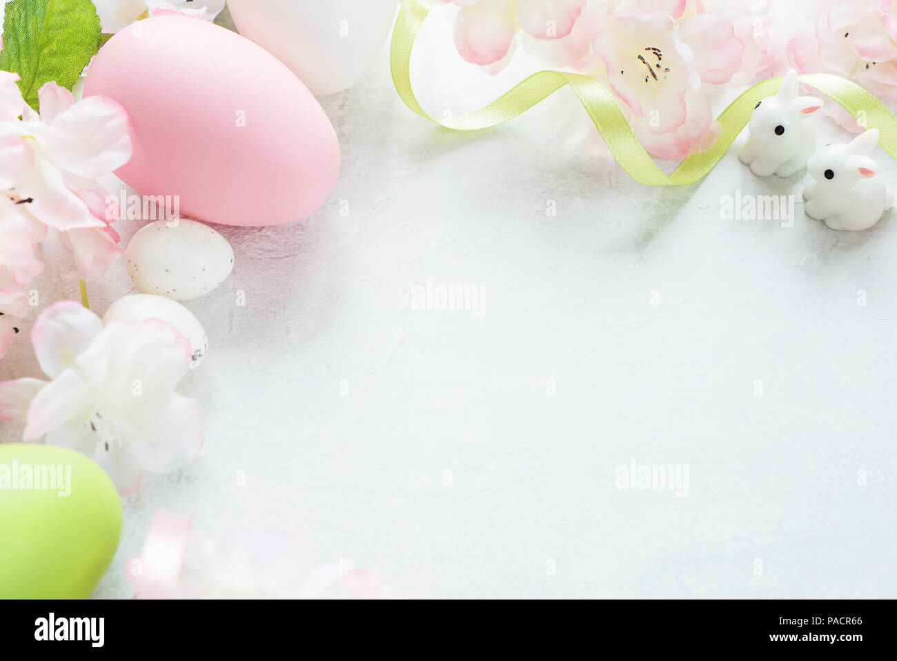 Hermosa delicada trama de Pascua con flores de cerezo rosa multicolor, huevos de Pascua y el conejo de Pascua sobre el fondo de piedra, con espacio de copia Foto de stock