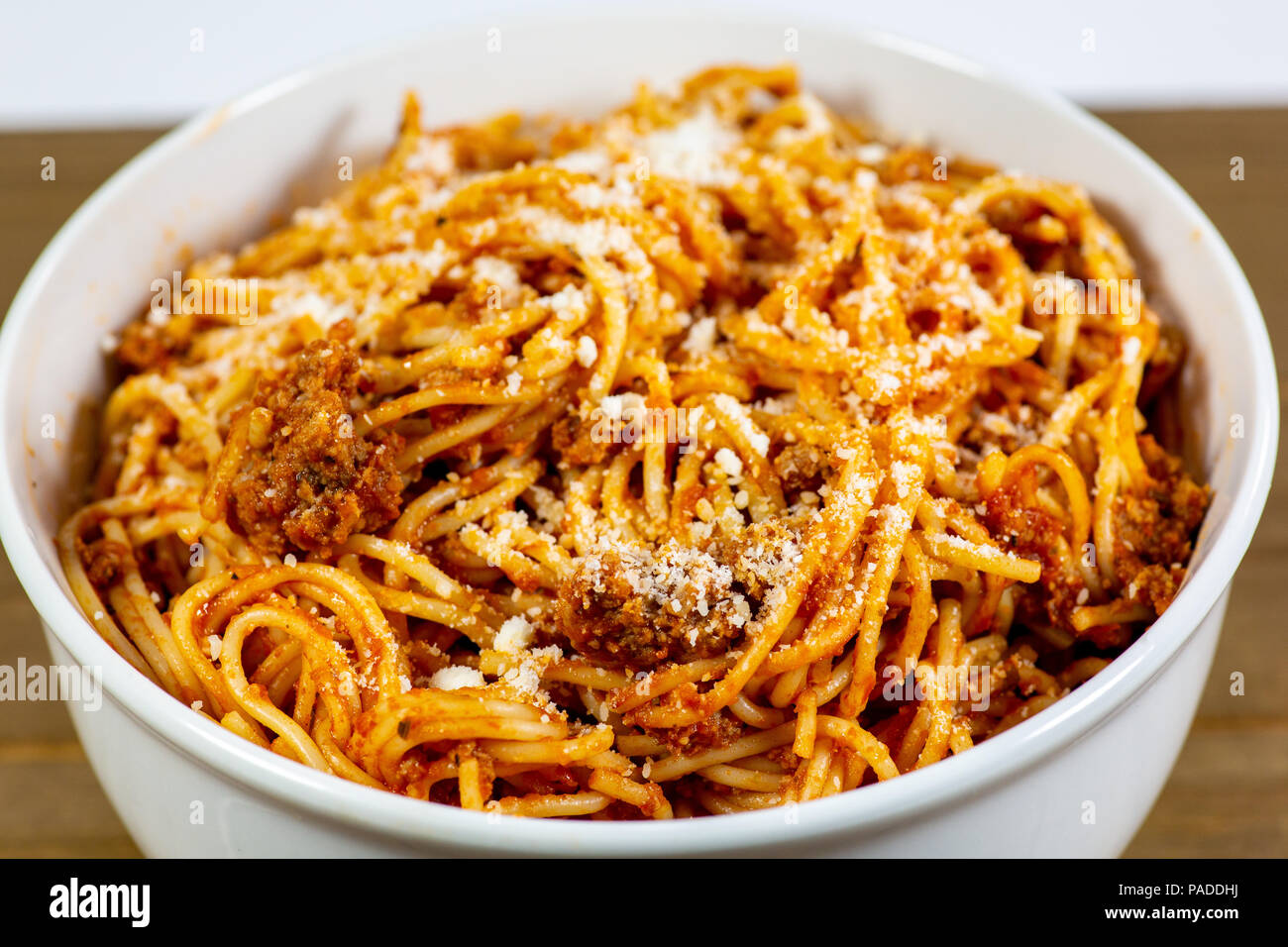 Los espaguetis a la Boloñesa en una cubeta blanca profunda sobre la mesa de la cocina de madera esperando ser comido Foto de stock