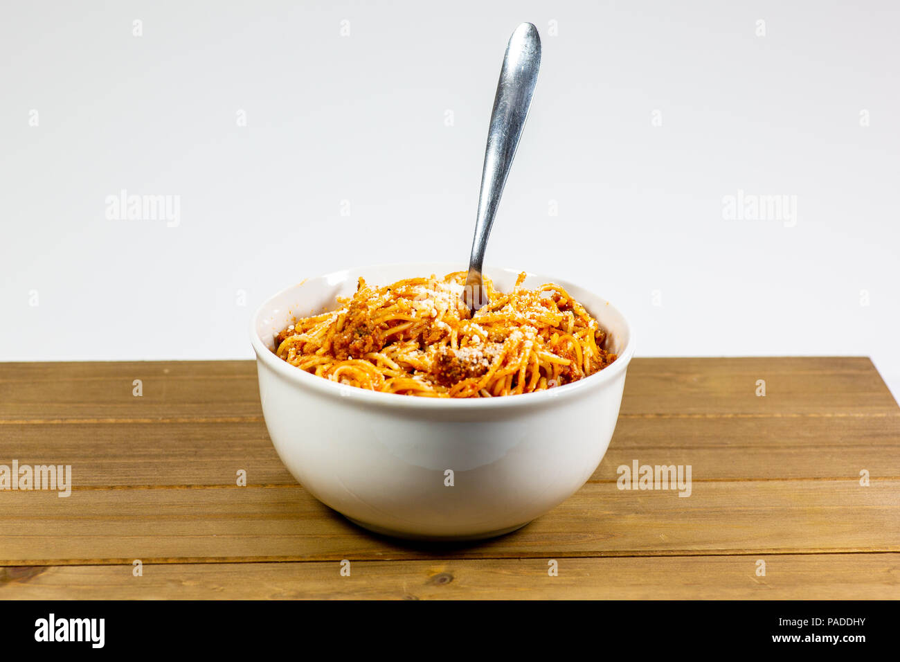 Los espaguetis a la Boloñesa en una cubeta blanca profunda sobre la mesa de la cocina de madera esperando ser comido Foto de stock