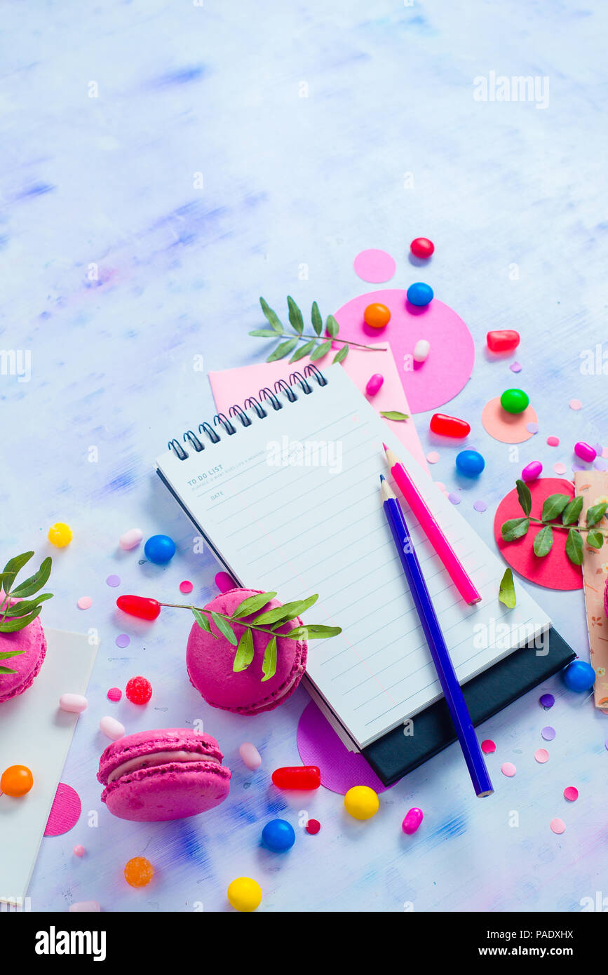 Colorido portátil con lápices y confeti sobre un fondo claro con espacio de copia. Paleta de color rosa y púrpura todavía la vida. Concepto de estilo de vida sencillo Foto de stock
