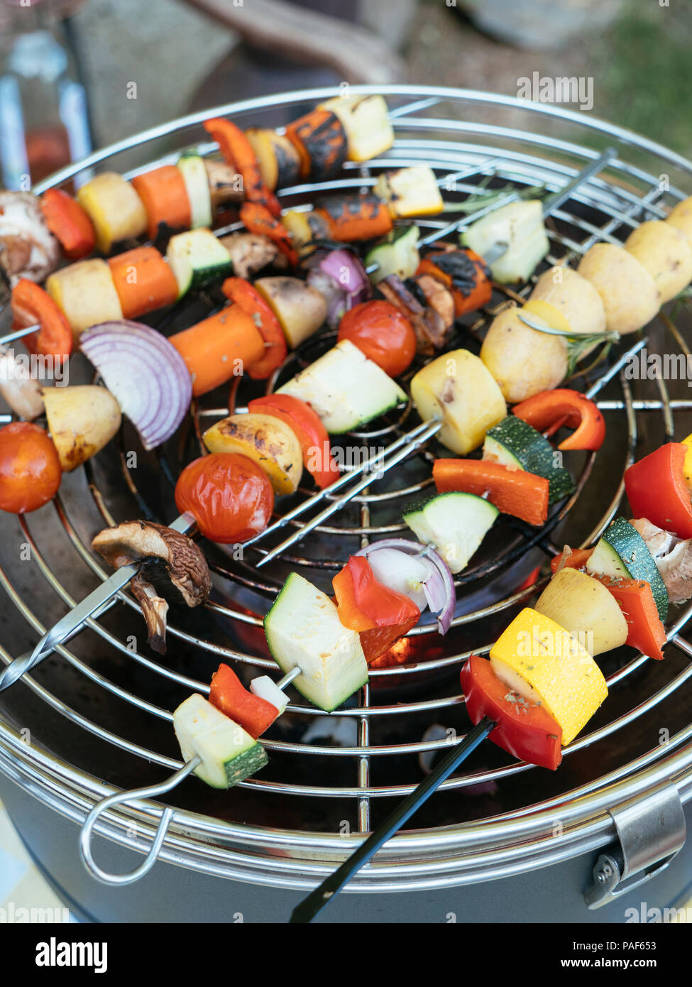 Brochetas wih mezcla de verduras (calabacín, patata, zanahoria, pimiento, setas) cocinar en una parrilla de carbón Foto de stock