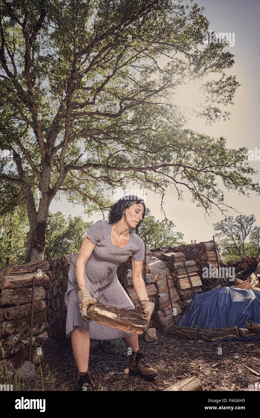 Una mujer embarazada con botas y un vestido vintage de madera apilado en una finca rural en el norte de California Fotografía stock - Alamy