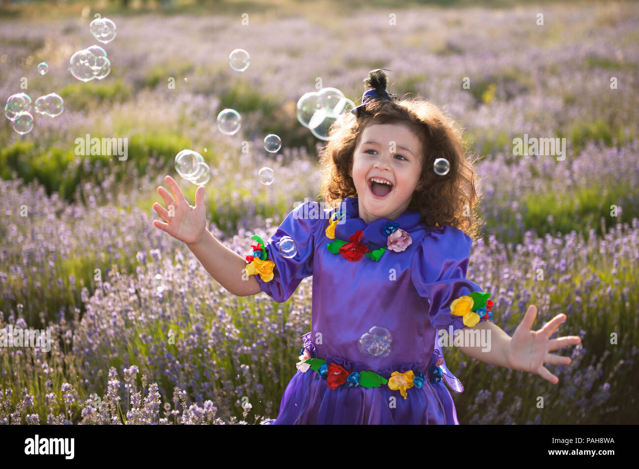 Feliz riendo niña jugando con pompas de jabón en el exterior del campo de  verano Fotografía de stock - Alamy