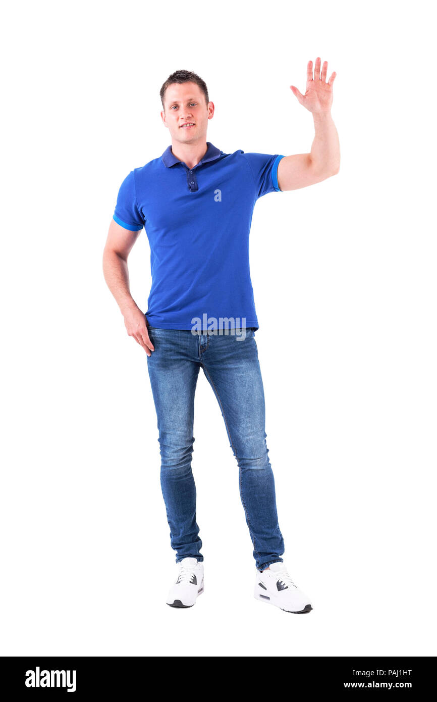 Jóvenes Adultos casual hombre en azul polo shirt agitando la mano y acogedor, mirando a la cámara. Cuerpo completo aislado sobre fondo blanco. Foto de stock