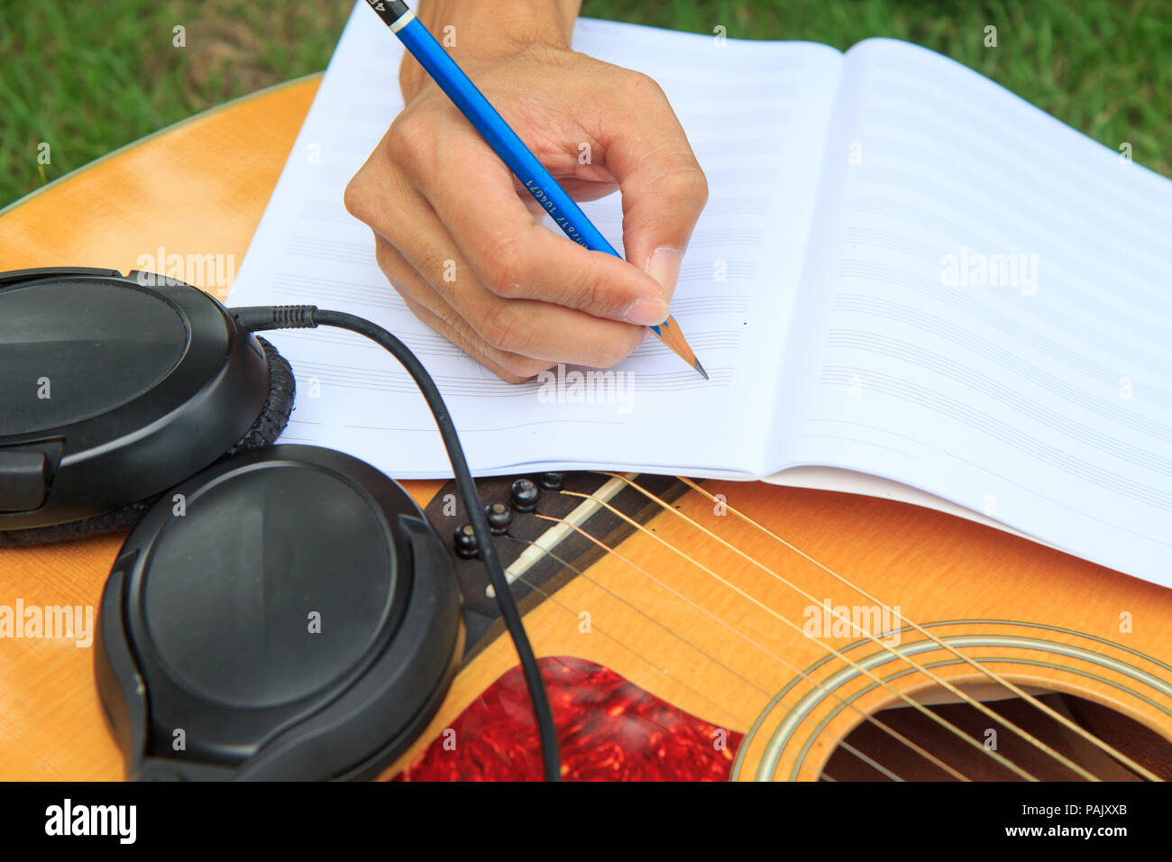 Compositor escribir nota de canción y utilizar la guitarra acústica para  jugar Fotografía de stock - Alamy