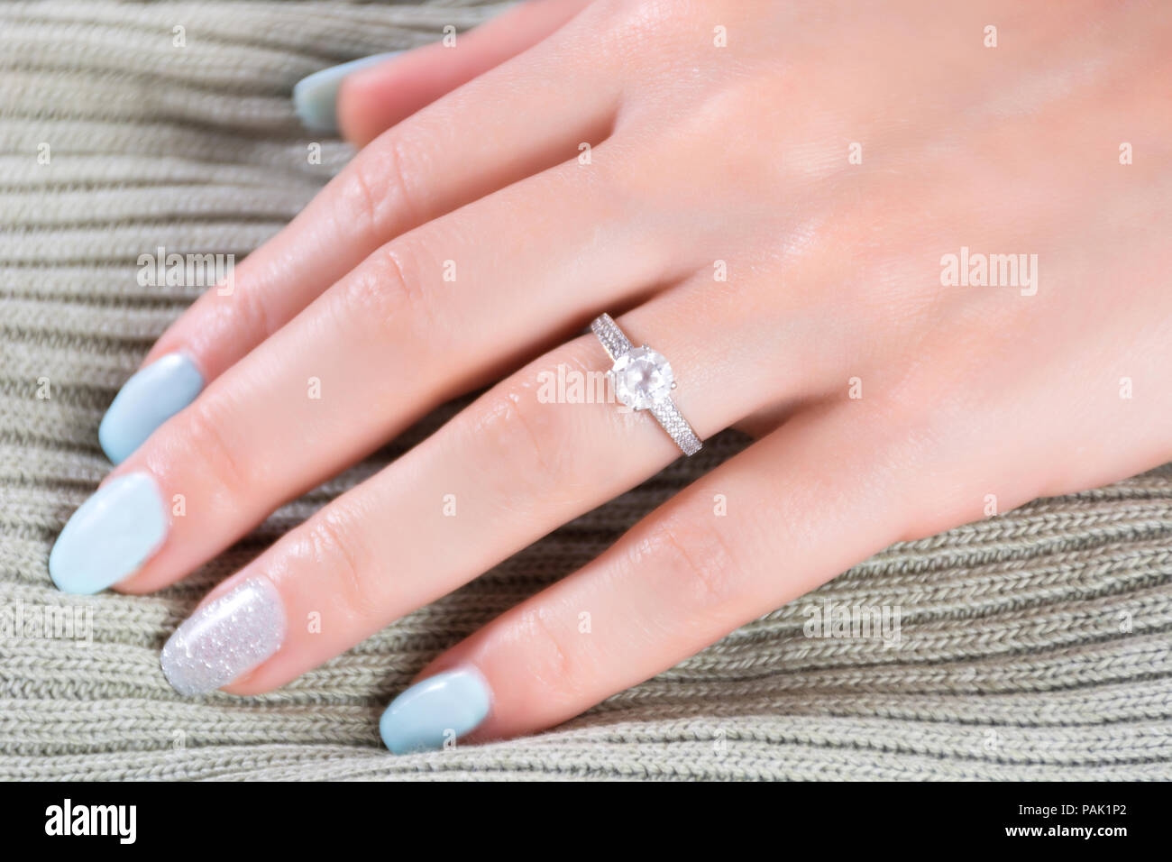 Diamantes anillos de compromiso de boda en el dedo femenino con uñas azul tejido de manicura y del fondo. Concepto de belleza y Fotografía de stock - Alamy
