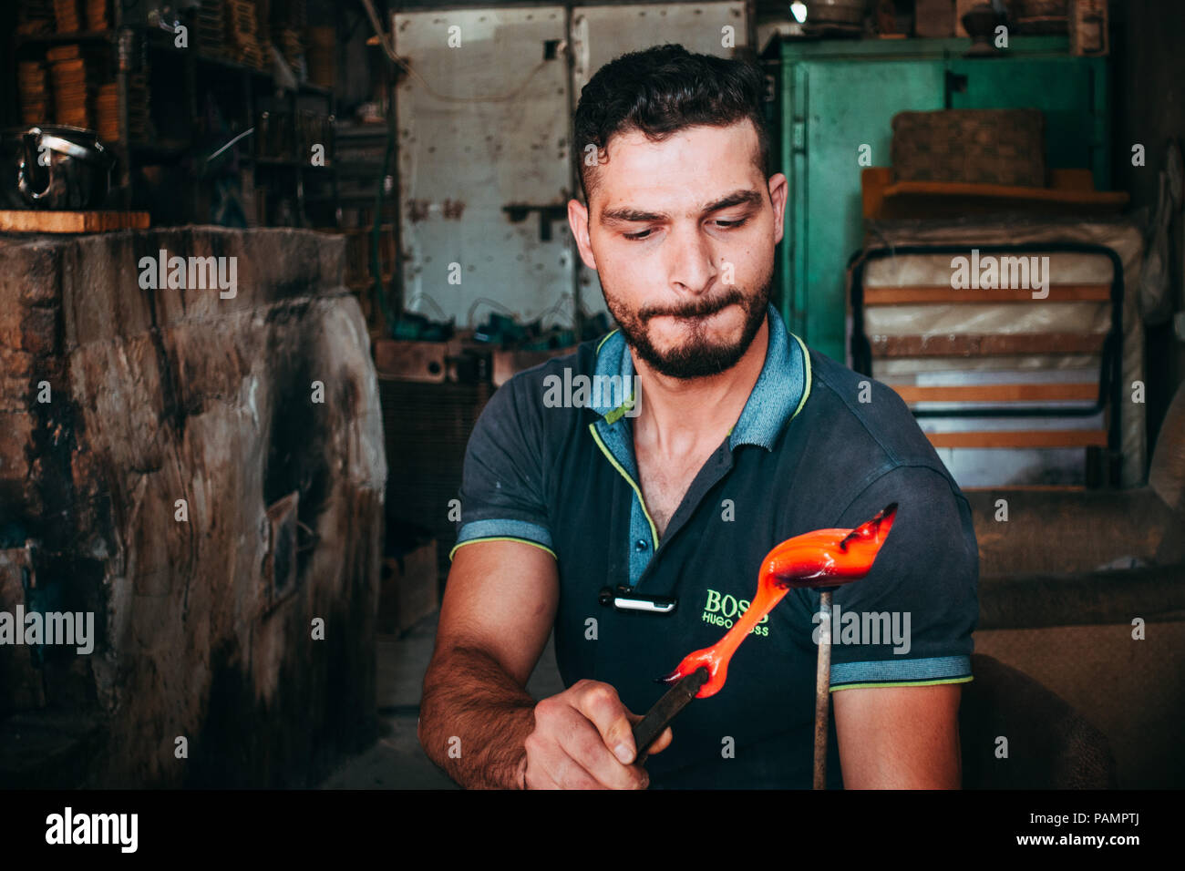 Un joven glassblower sopla un cisne de cristal en un taller en Hebrón, Palestina Foto de stock