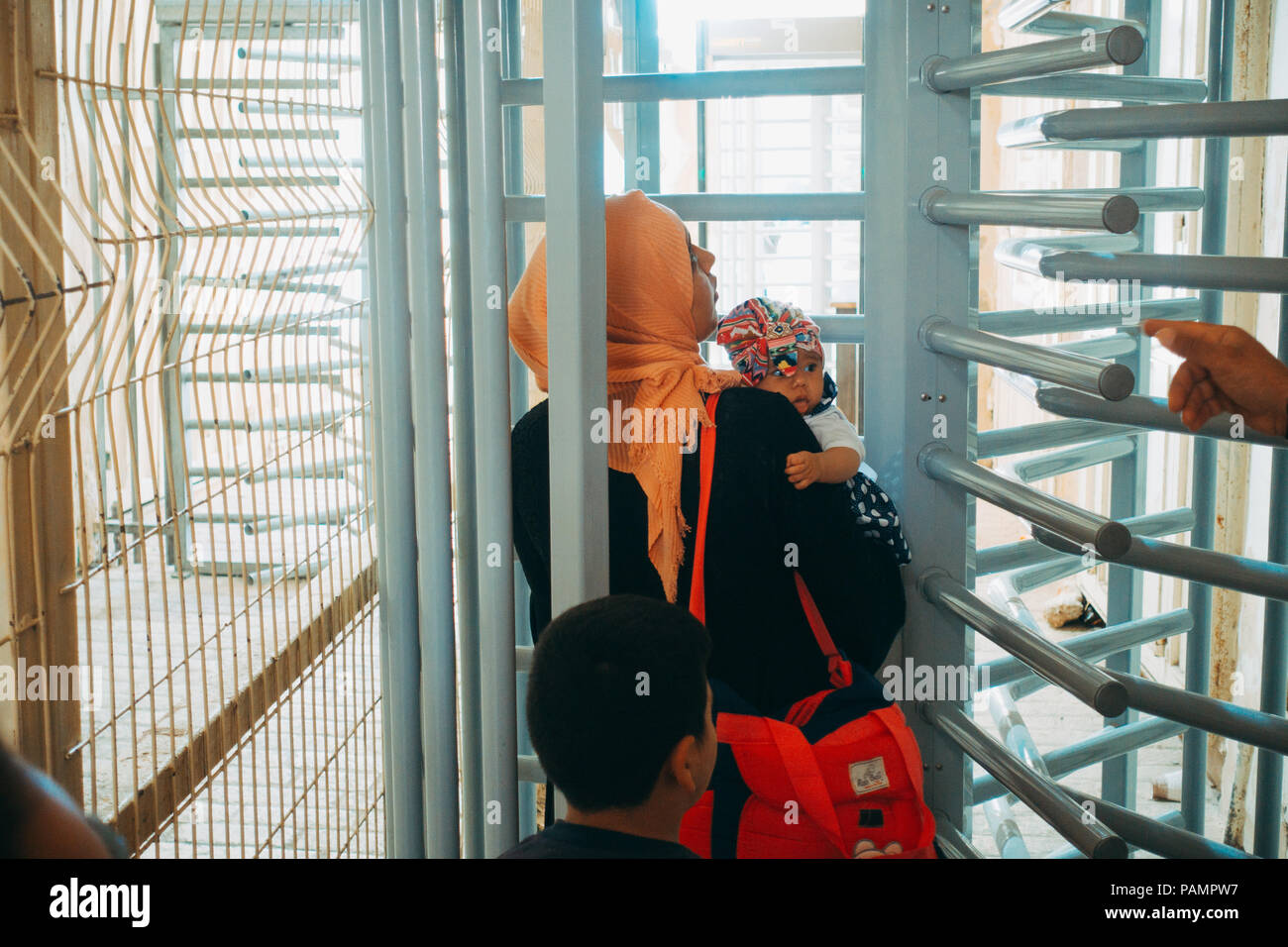 Una mujer musulmana y su hijo esperar a ser admitido en la Mezquita de Ibrahimi, por soldados de las Fuerzas de Defensa de Israel en un puesto de control militar en Hebrón, en la Ribera Occidental Foto de stock