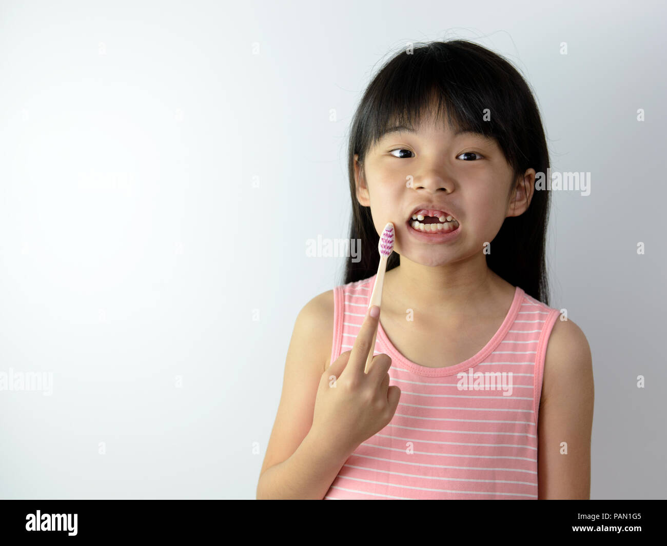 Poco de Asia chica sin dientes frontales sosteniendo un cepillo de dientes  Fotografía de stock - Alamy