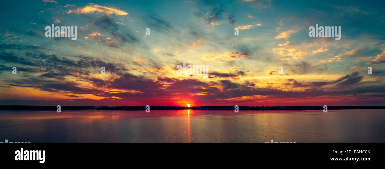 Antena drone vistas panorámicas de colorido de la puesta del sol sobre el lago, el reflejo del sol en el agua, el cielo nublado tras la lluvia sin viento, Rusia Foto de stock