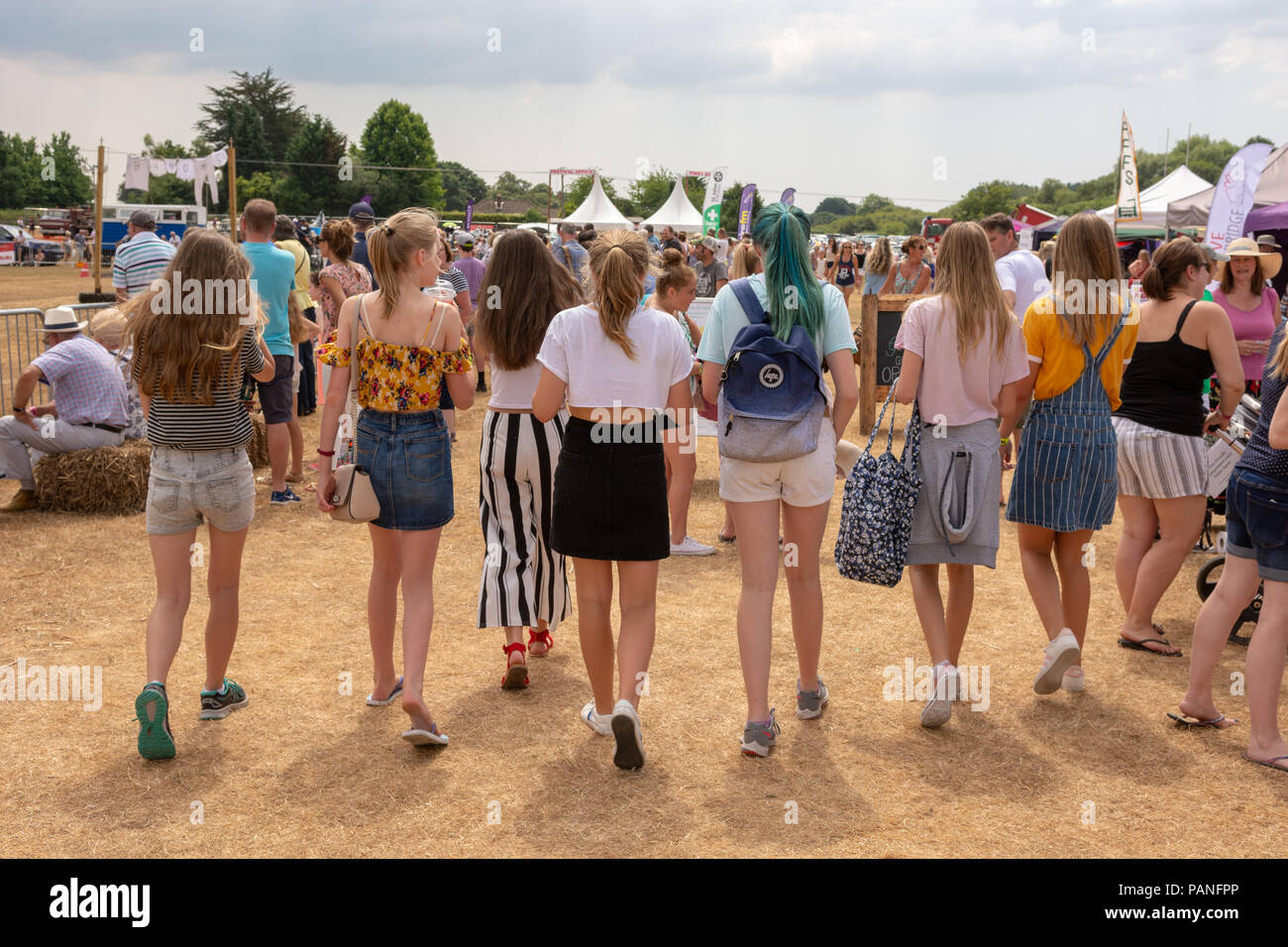 Un grupo de adolescentes a caminar en una línea en un país justo en Hampshire en verano. Foto de stock